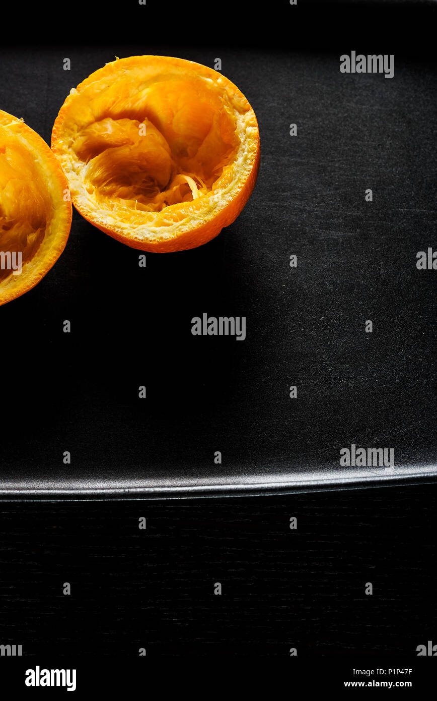Used orange skins with dramatic light on black background. Vertical image. Stock Photo