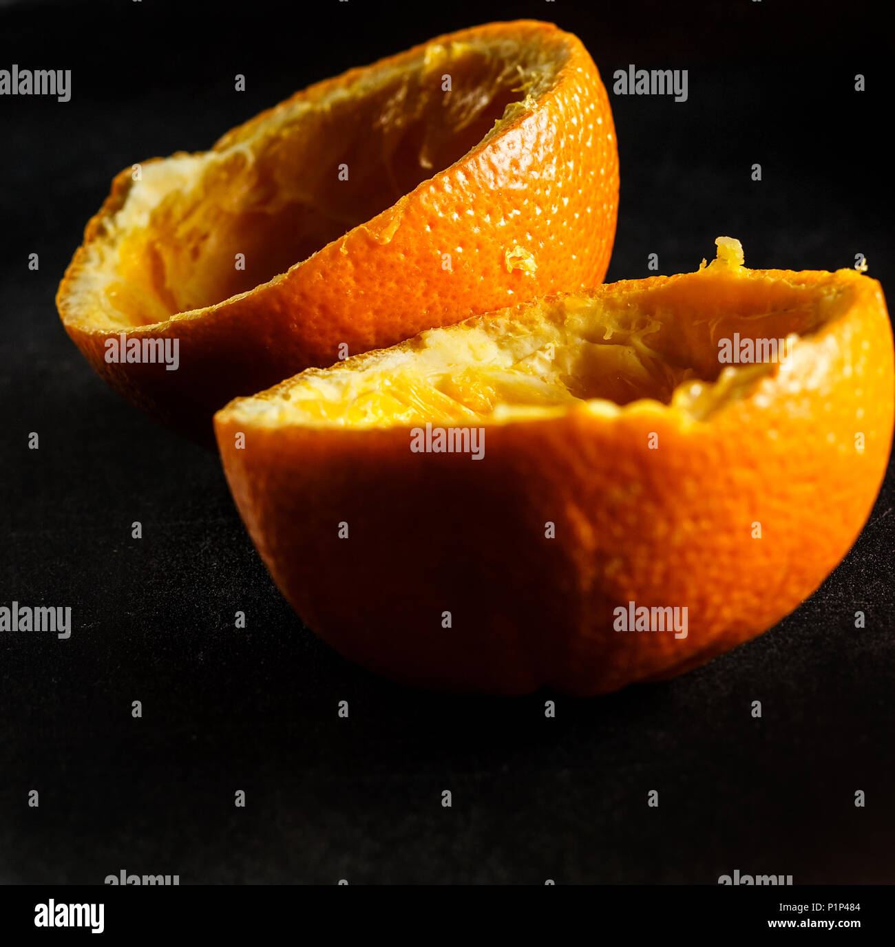 Used orange skins with dramatic light on black background. Square image. Stock Photo