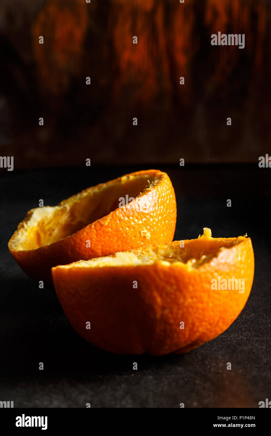 Used orange skins with dramatic light on black background. Vertical image. Stock Photo