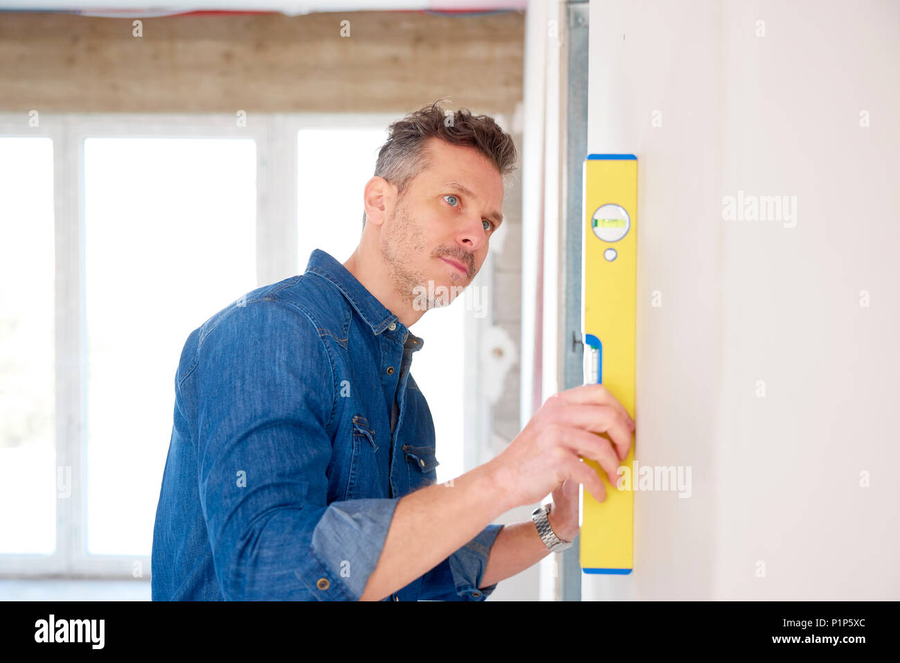 Handyman using spirit level while working on construction site. Stock Photo