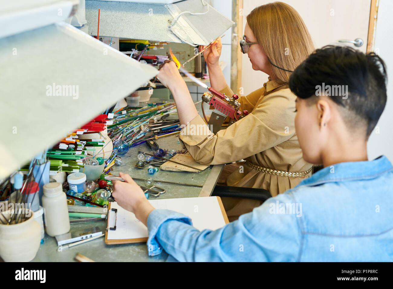 Two Female Artists Collaborating in Glassworking Shop Stock Photo