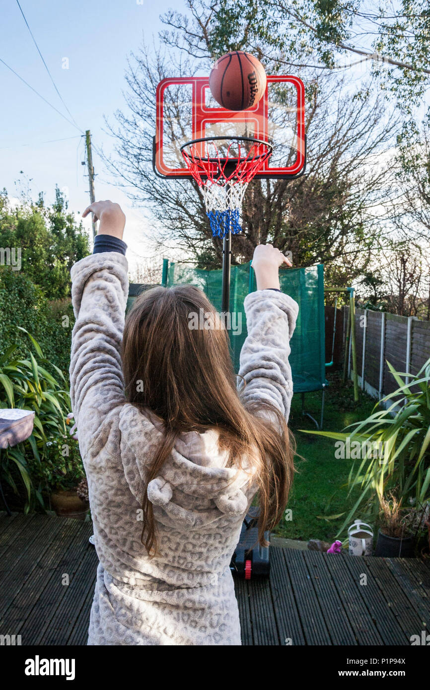 Girl person, shooting a basket, playing basketball in the garden, ball in transit, ball in the air, basket ball, Dublin Ireland Stock Photo
