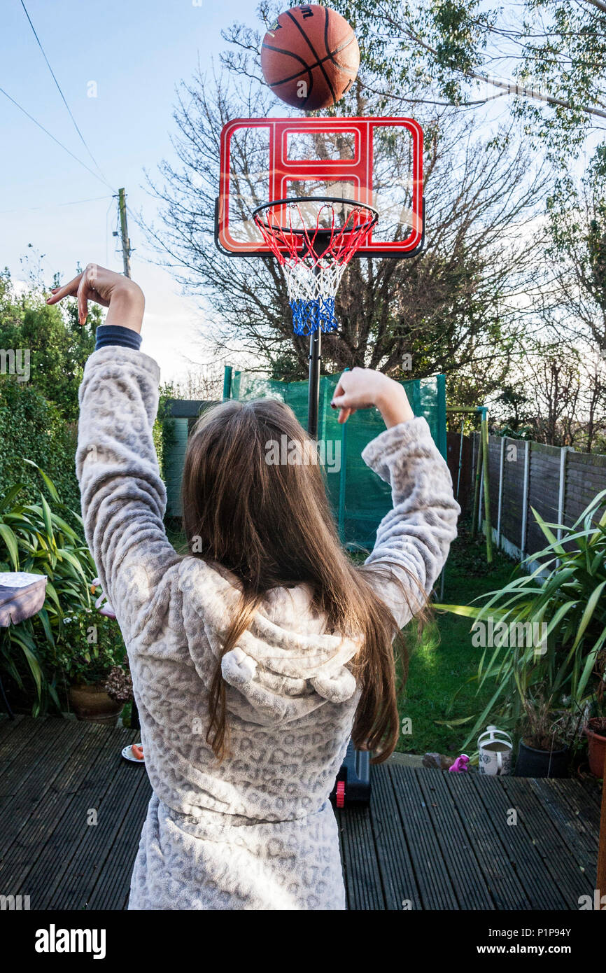 Girl person, shooting a basket, playing basketball in the garden, ball in transit, ball in the air, basket ball, Dublin Ireland Stock Photo