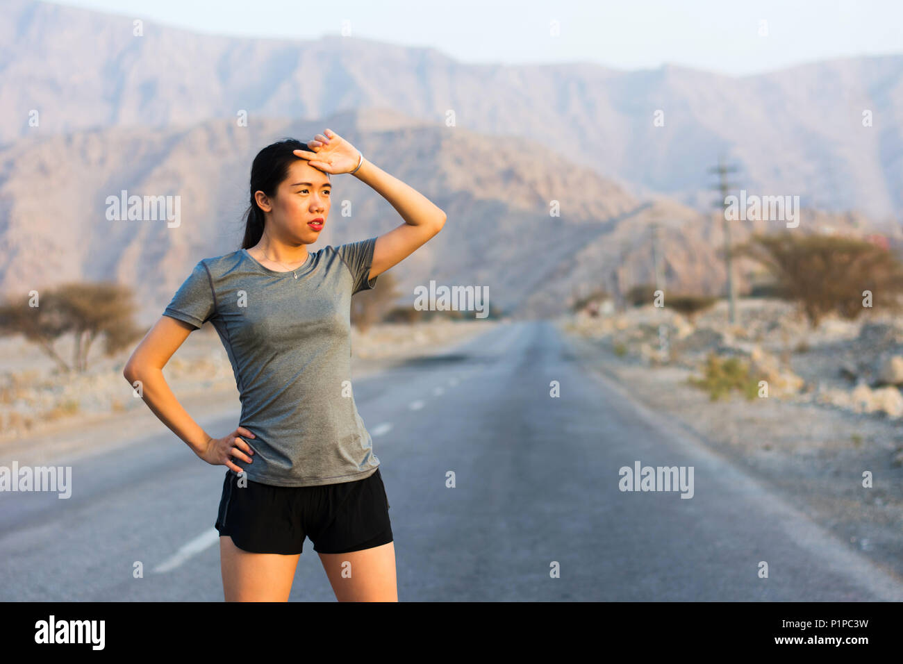 Tired runner taking a rest on a desert road Stock Photo