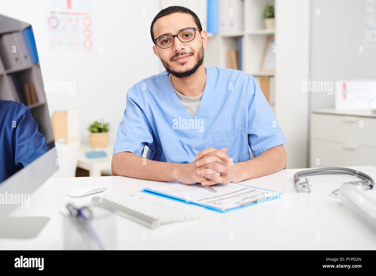Middle-Eastern Doctor Posing at Desk Stock Photo