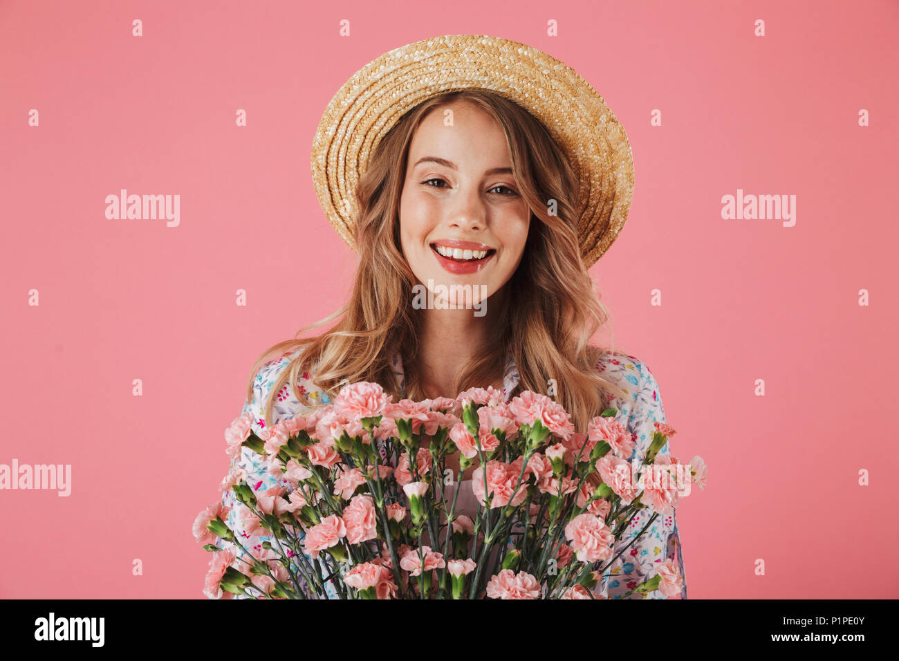 Portrait of a cheerful young woman in summer dress and straw hat ...