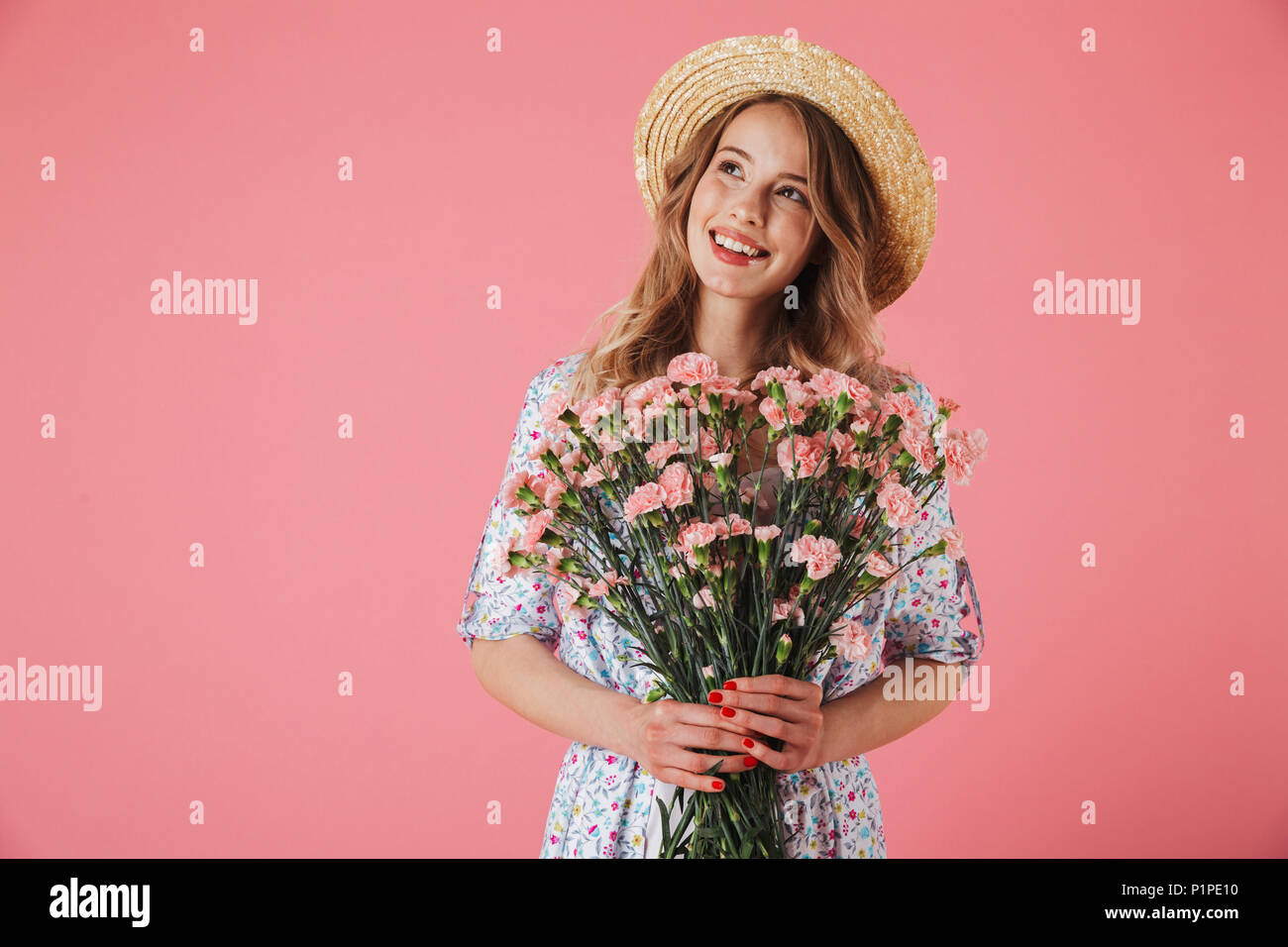 Portrait of a cheerful young woman in summer dress and straw hat ...