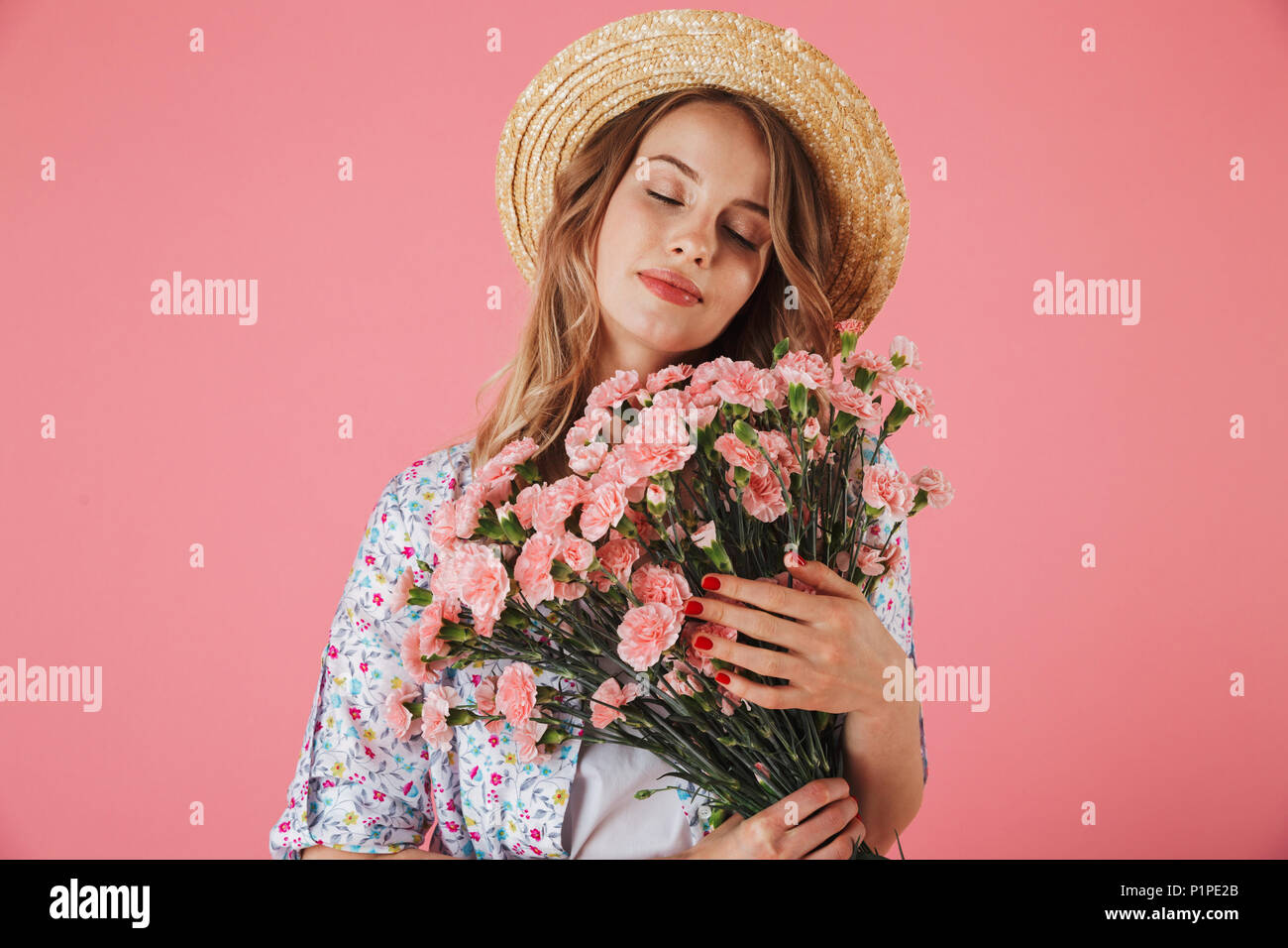 Portrait of a sensual young woman in summer dress and straw hat holding ...