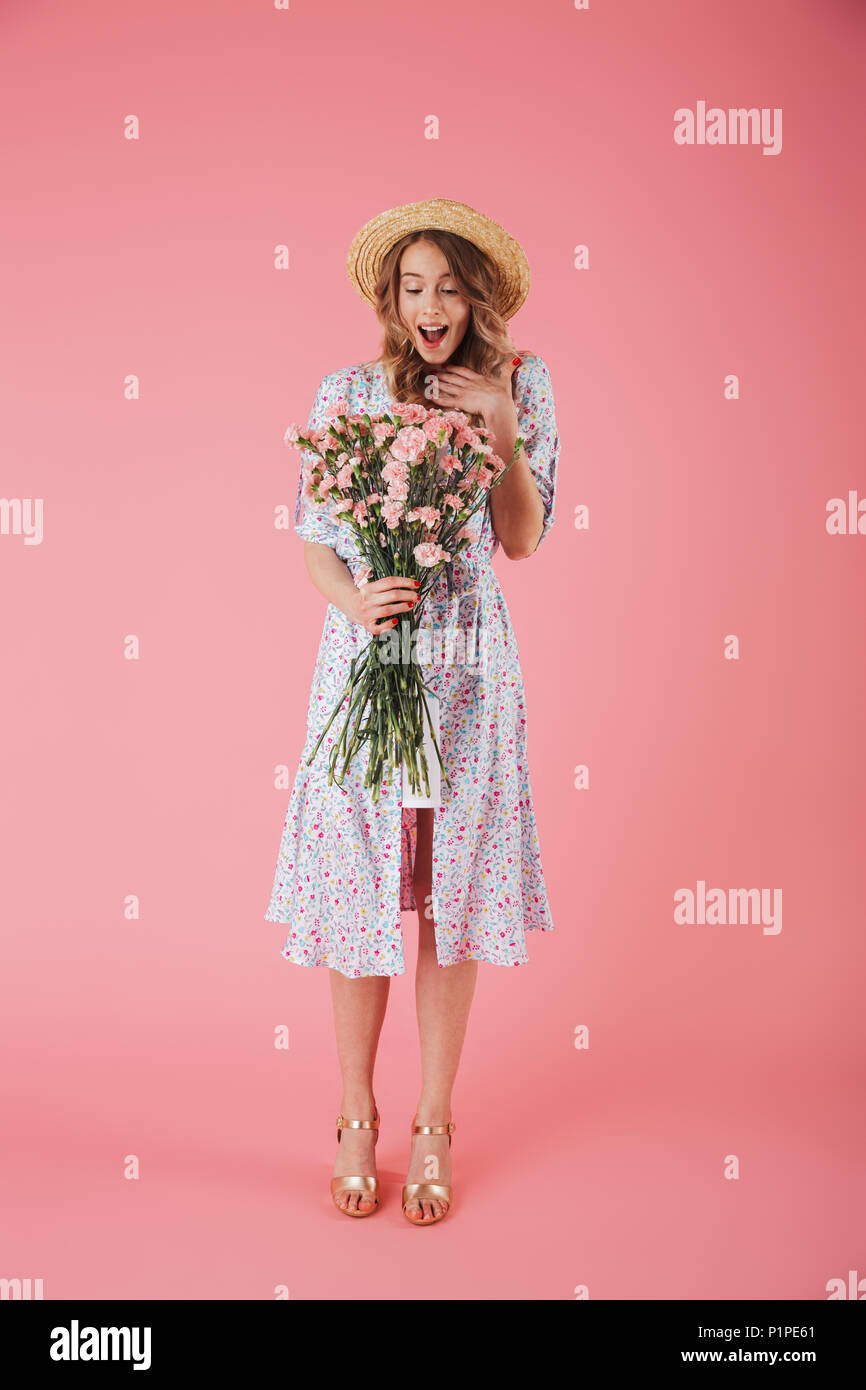 Full length portrait of a happy young woman in summer dress and straw ...