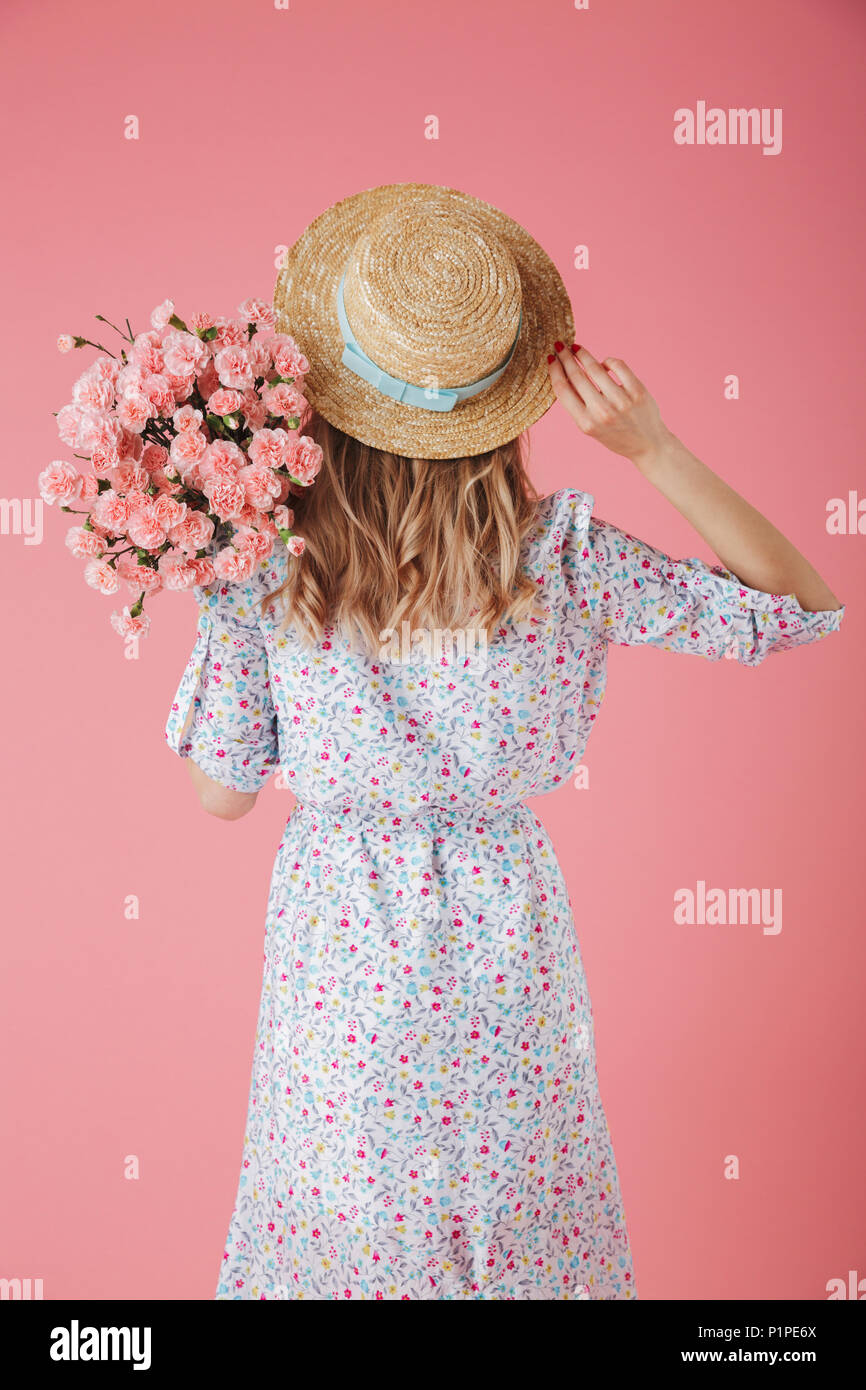 Back view portrait of a pretty young woman in summer dress and straw ...