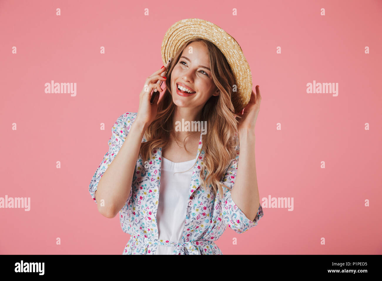 Portrait of a cheerful young woman in summer dress and straw hat ...