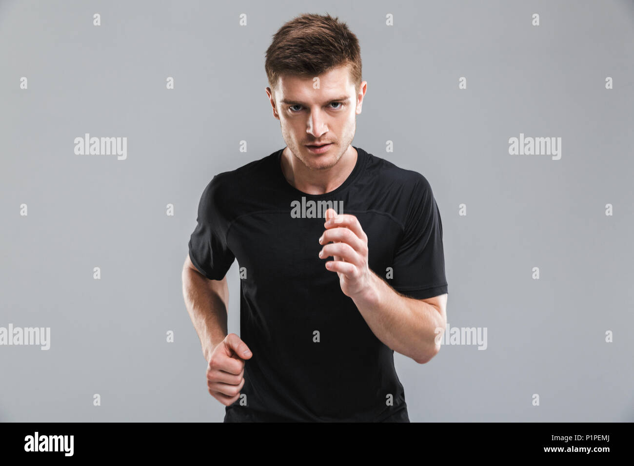 Running Fast Image Portrait of a confident young sportsman running fast isolated over gray ...
