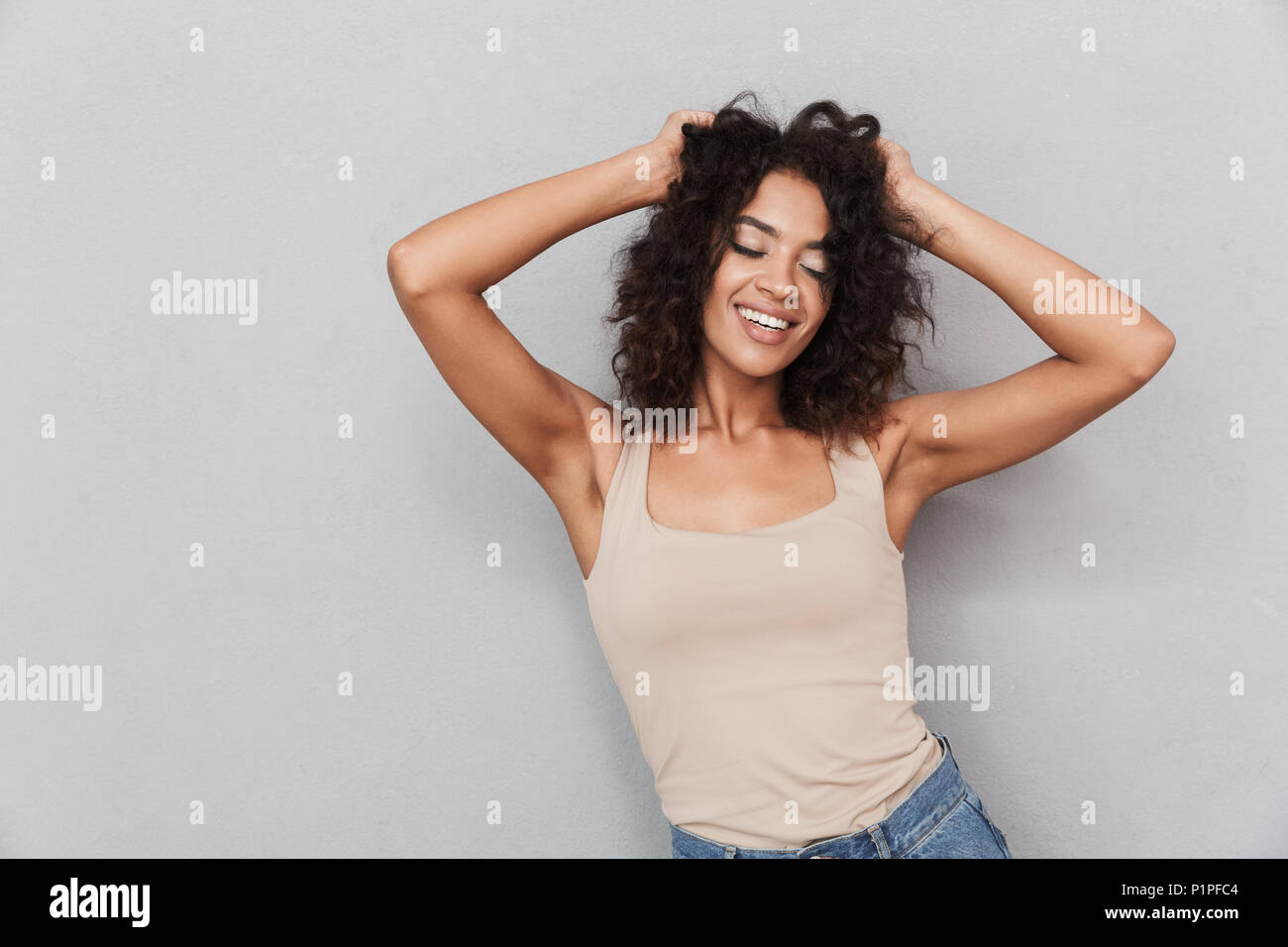 Portrait of a pretty young african woman holding arms in her hair over ...
