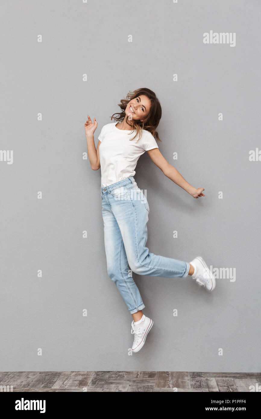 Full length portrait of a happy young woman jumping and celebrating ...