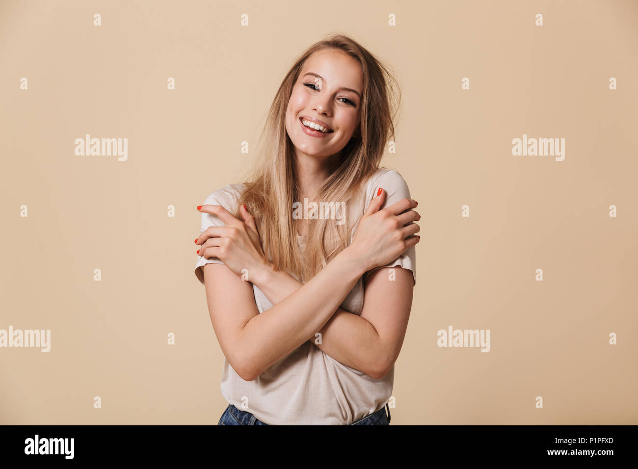 Portrait of a happy casual girl looking at camera isolated over beige ...