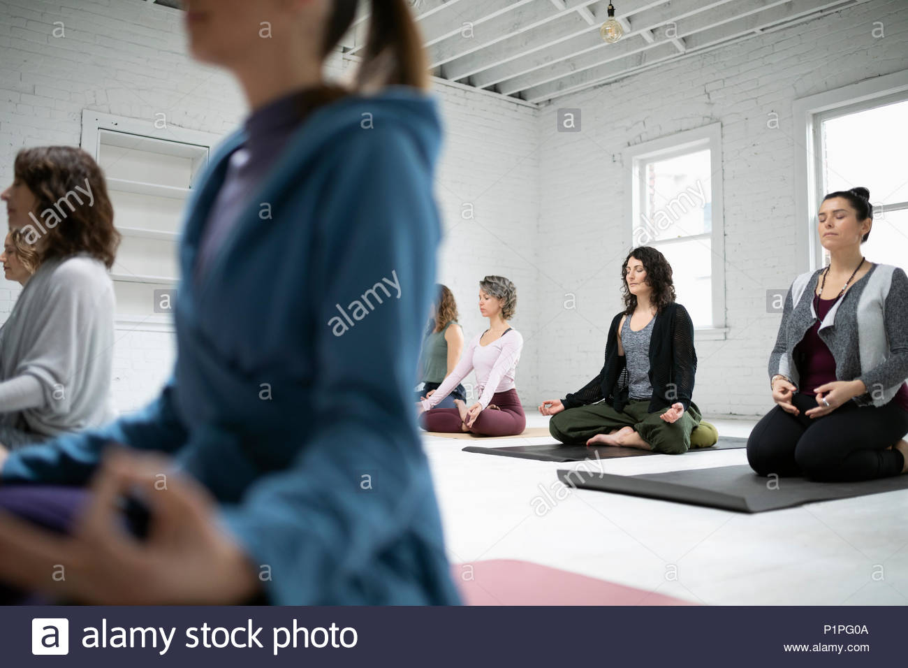 Women sitting in lotus position meditation in yoga class Stock Photo