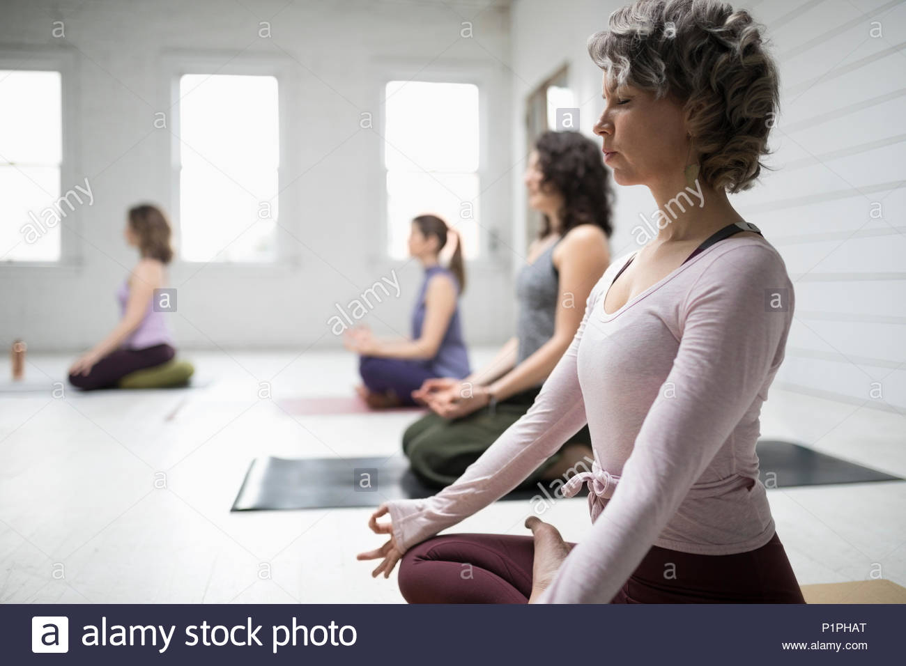 Serene woman practicing lotus position meditation in yoga class Stock Photo
