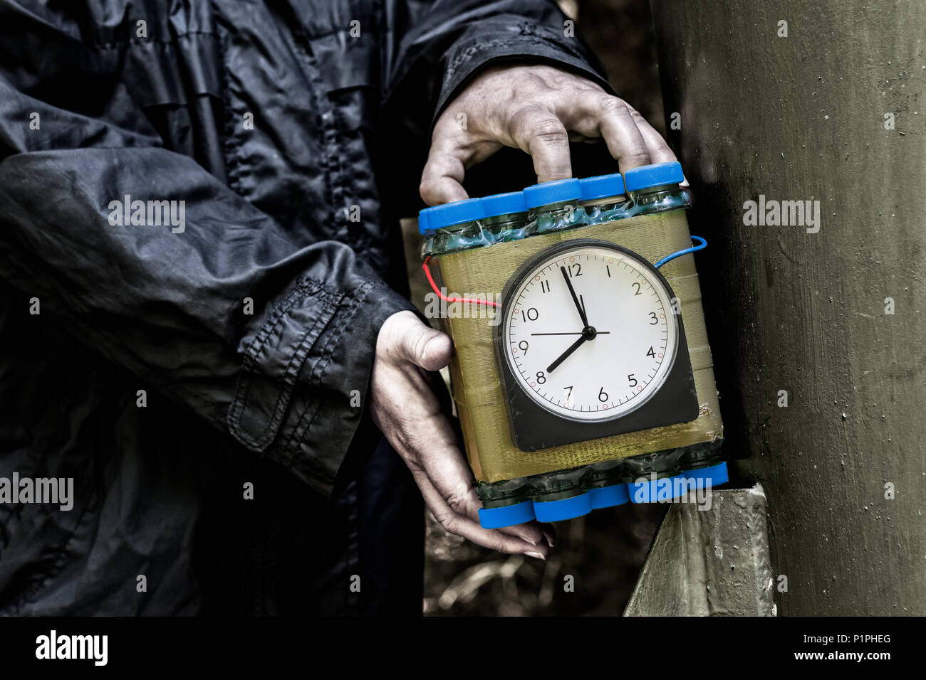 Terrorist holding a timed bomb in his hands. Dangerous aggressor and dummy of the explosive device. Idea of terrorist attack, security and protection. Stock Photo