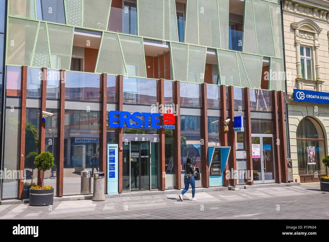VUKOVAR, CROATIA - MAY 14, 2018 : A young woman walking in front of the Erste bank building in Vukovar, Croatia. Stock Photo