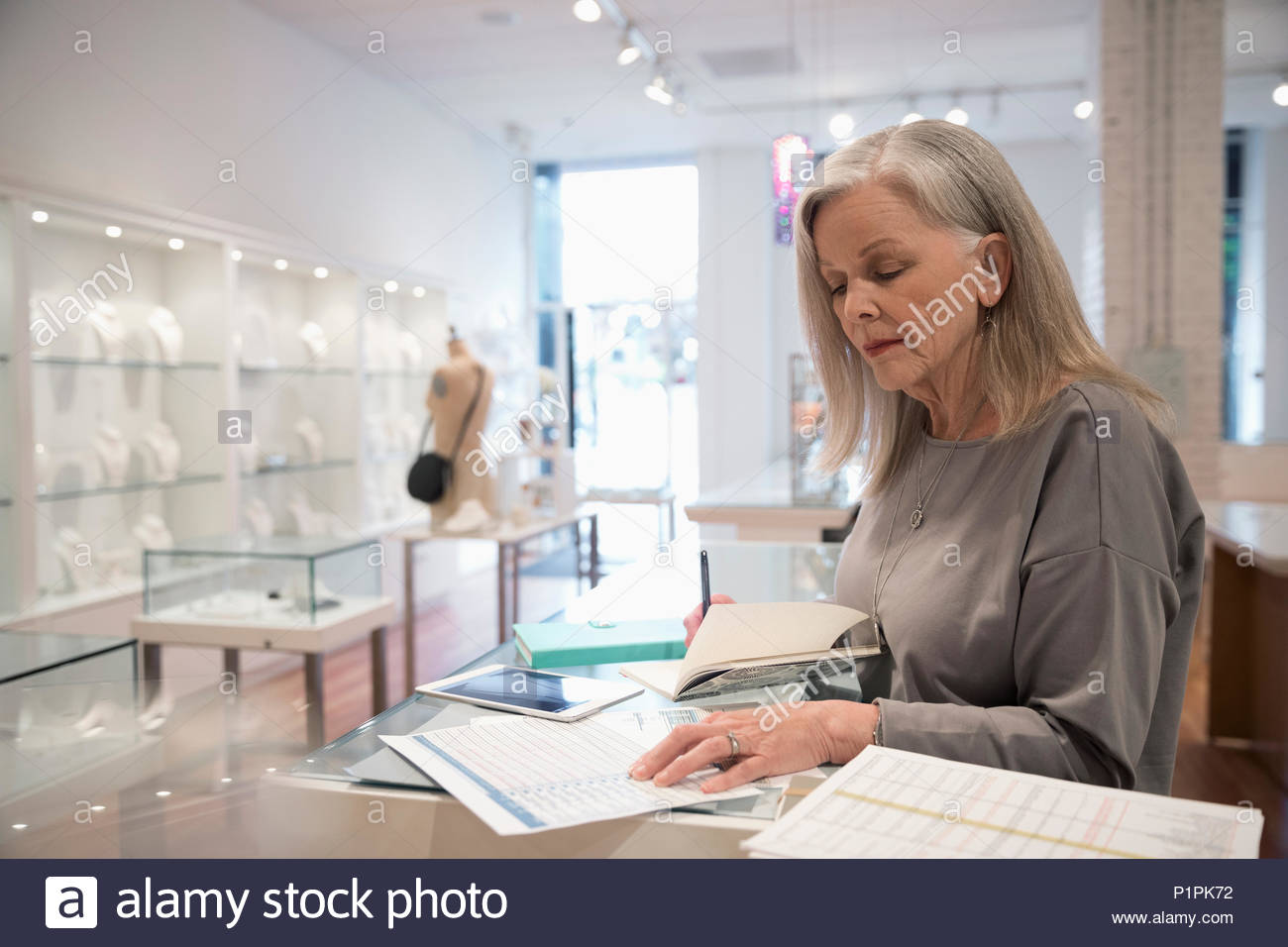 Senior jewelry boutique business owner paying bills Stock Photo