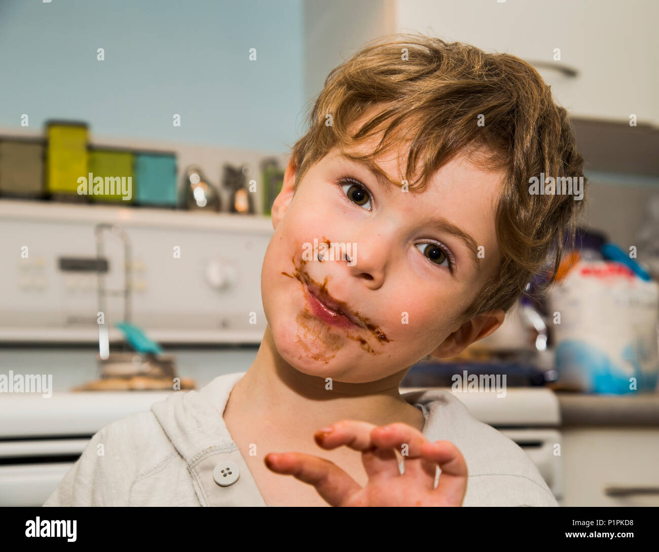 A grinning young boy icking fingers and getting messy after making fudge; Langley, British Columbia, Canada Stock Photo