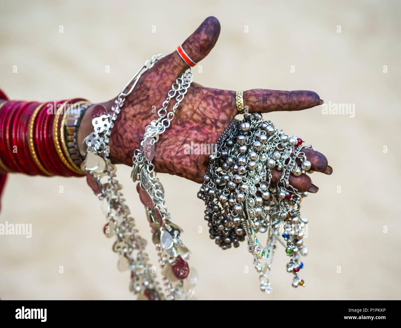 A woman's hand covered in henna body art and holding silver jewelry; Jaisalmer, Rajasthan, India Stock Photo