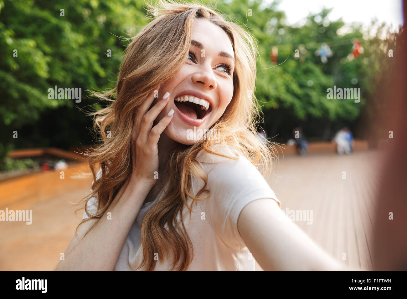 Close up of a laughing young girl taking selfie with outstretched hand ...