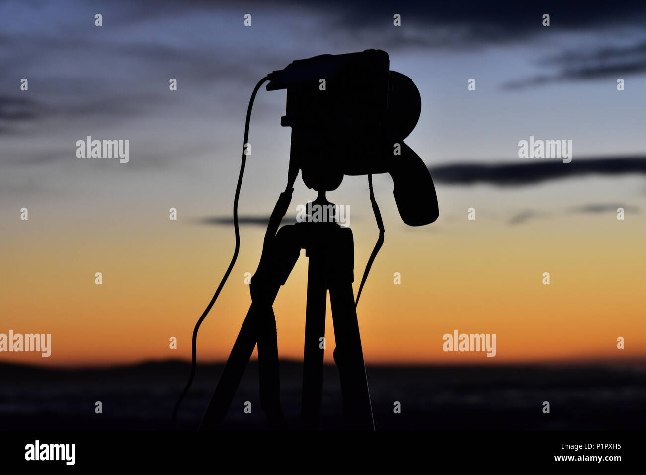 Early morning photography, greeted by a beautiful sunrise. This photo captures both the silhouette of a camera and the vivid colours of the sunrise. Stock Photo