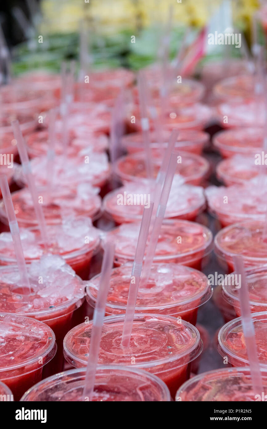 a large quantity of smoothies or fruity juice drinks lined up in rows for sale at a fresh fruit