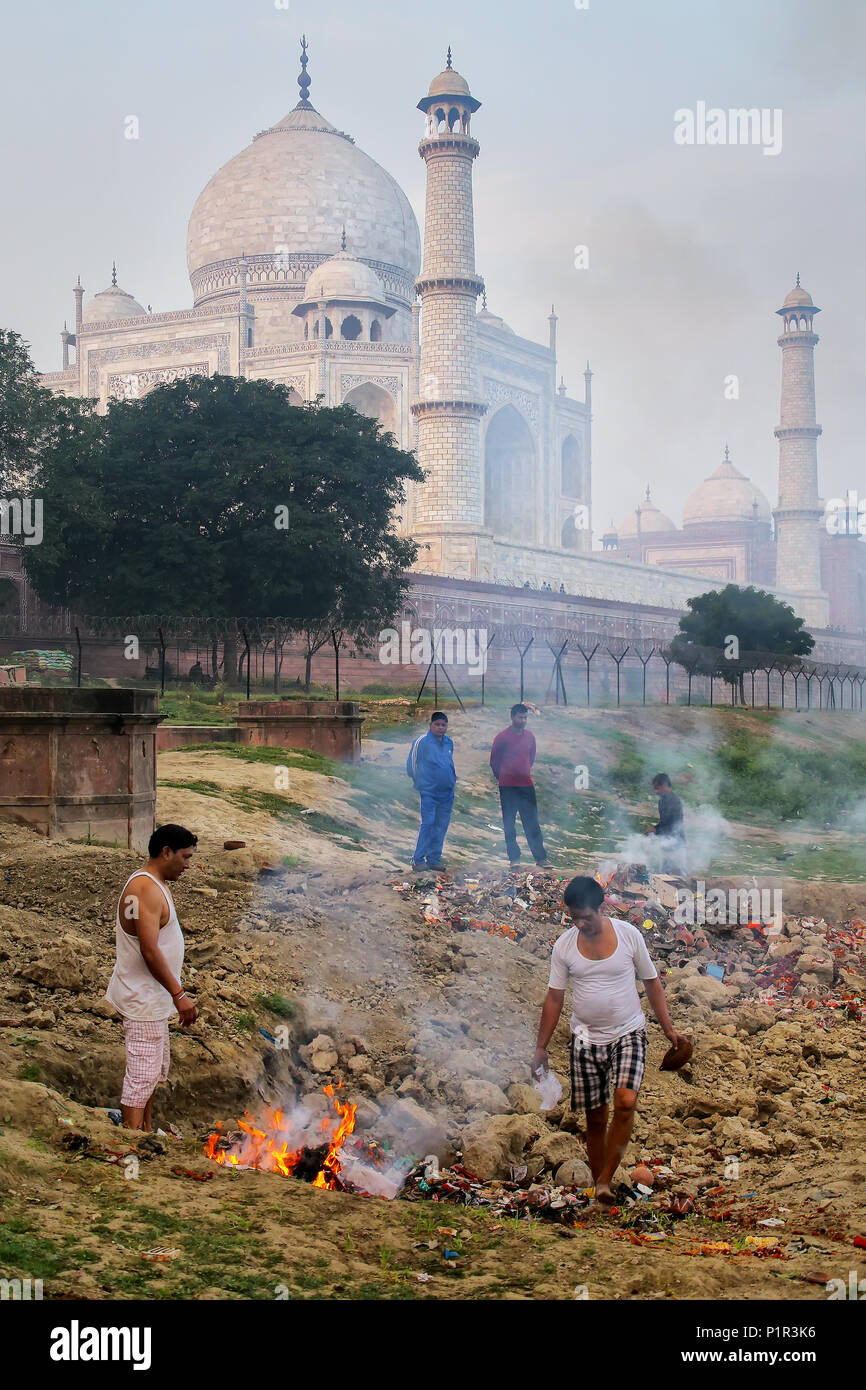 Local men burning garbage on the bank of Yamuna river near Taj Mahal, Agra, Uttar Pradesh, India. Taj Mahal was designated as a UNESCO World Heritage  Stock Photo