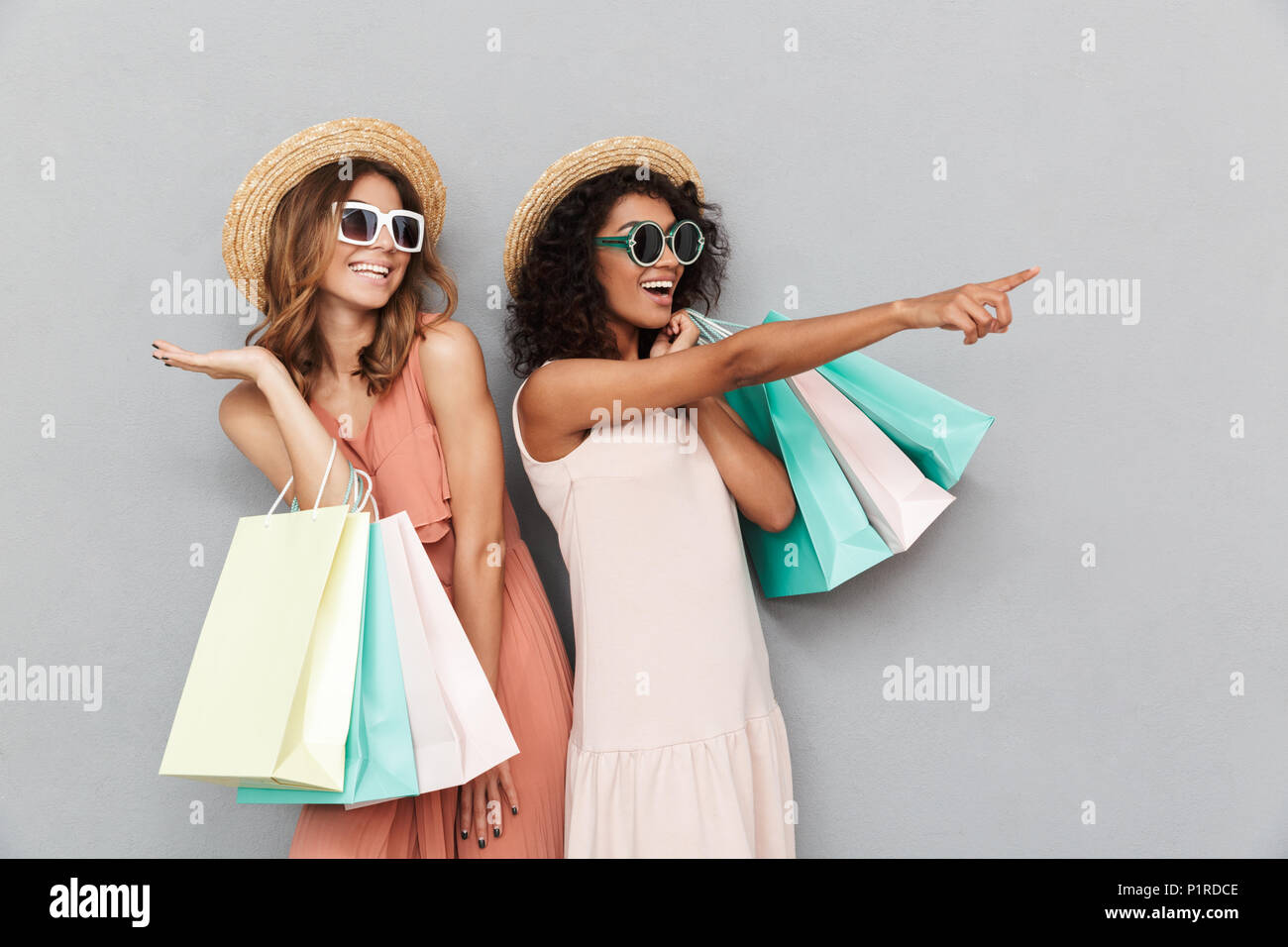 Portrait of two smiling young women dressed in summer clothes holding ...