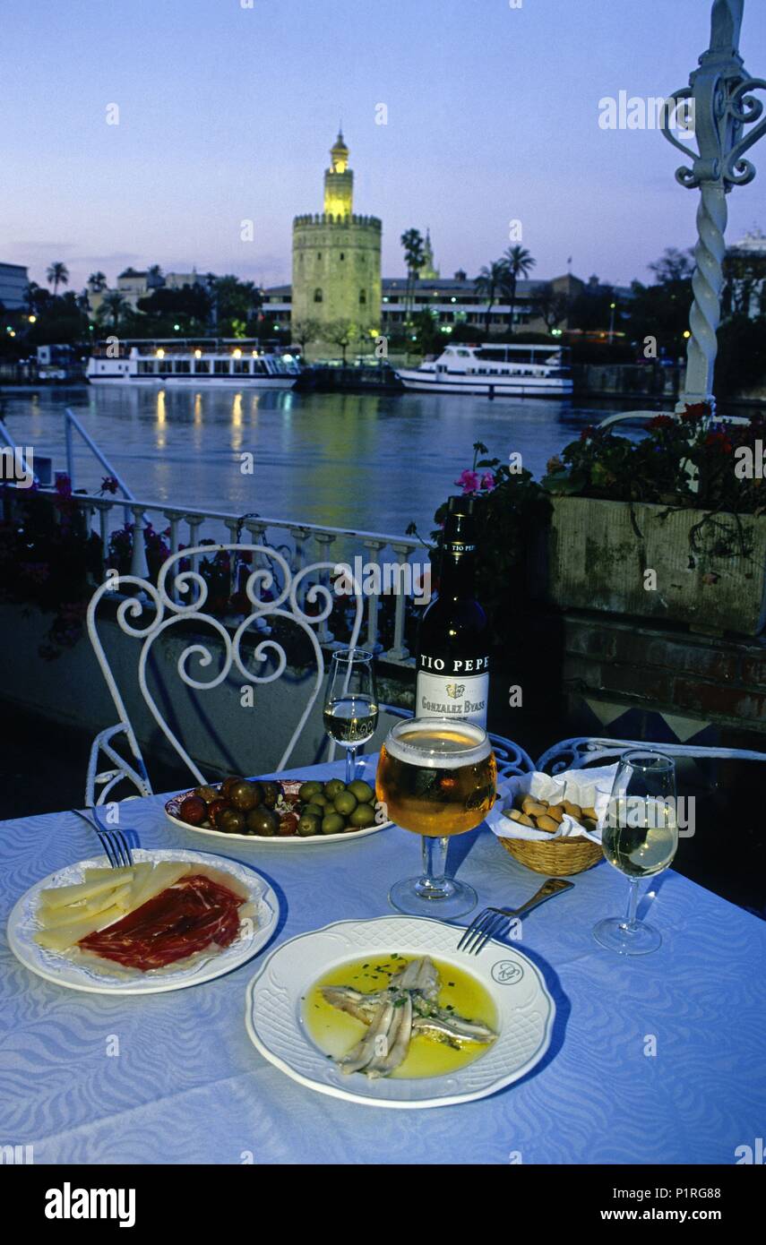 'Río Grande' Bar-Restaurant at the Barrio de Triana district; 'tapas' (kind of snacks); Guadalquivir river and 'Torre de Oro' tower at the background. Stock Photo