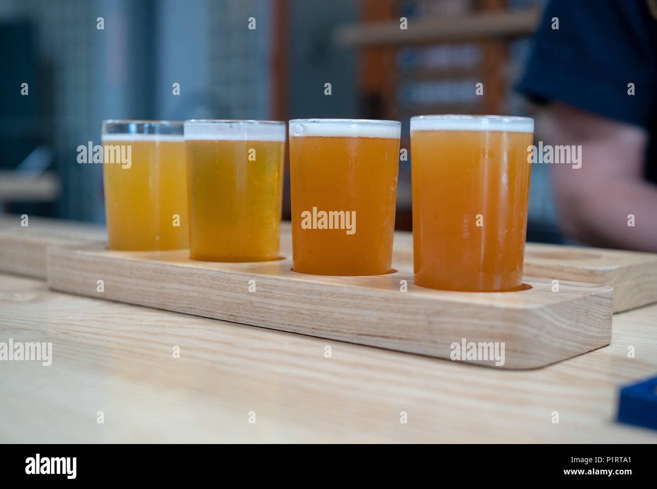 A flight of light colored craft beers sitting on wooden plank on a bar ...