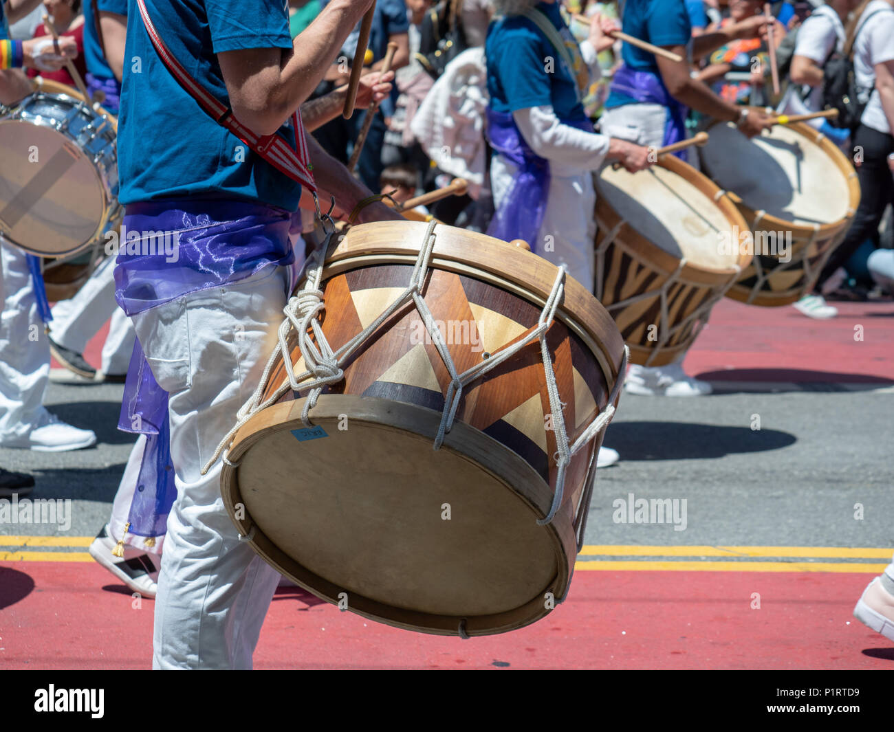 A mexican marching band beats on drums while walking down streets of