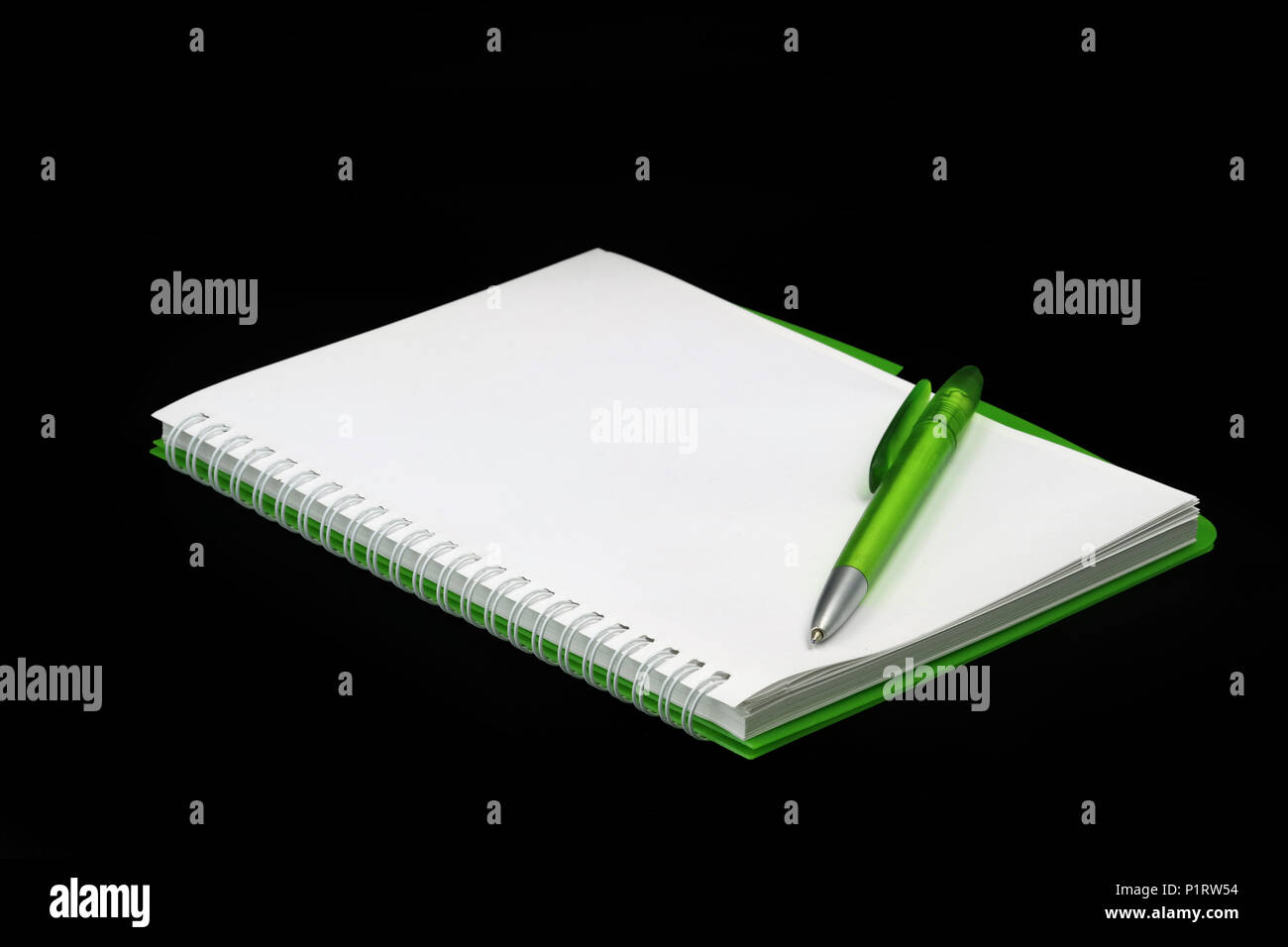 Blank green notepad with ballpoint pen isolated on black background Stock Photo