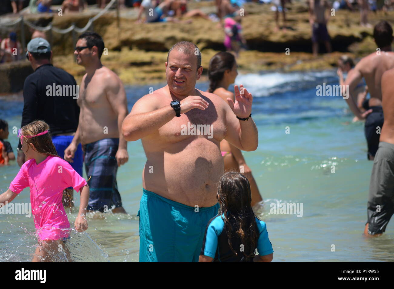 An overweight, obese man standing in the sea by beach Stock Photo