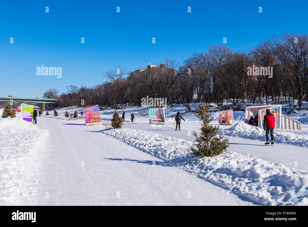 People walking and skating along the Red River Mutual Trail in Winnipeg, where artistic warming huts are on display; Winnipeg, Manitoba, Canada Stock Photo