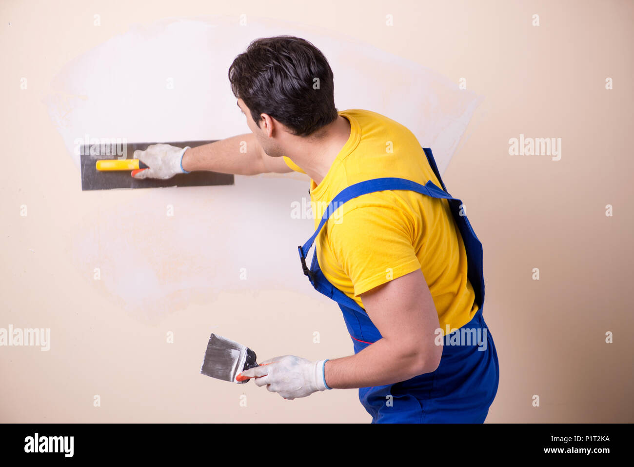Young contractor employee applying plaster on wall Stock Photo