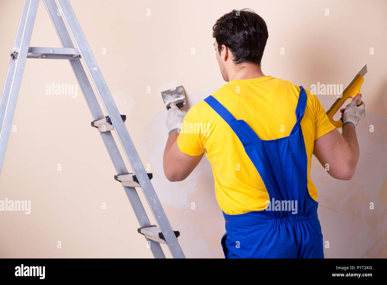 Young contractor employee applying plaster on wall Stock Photo