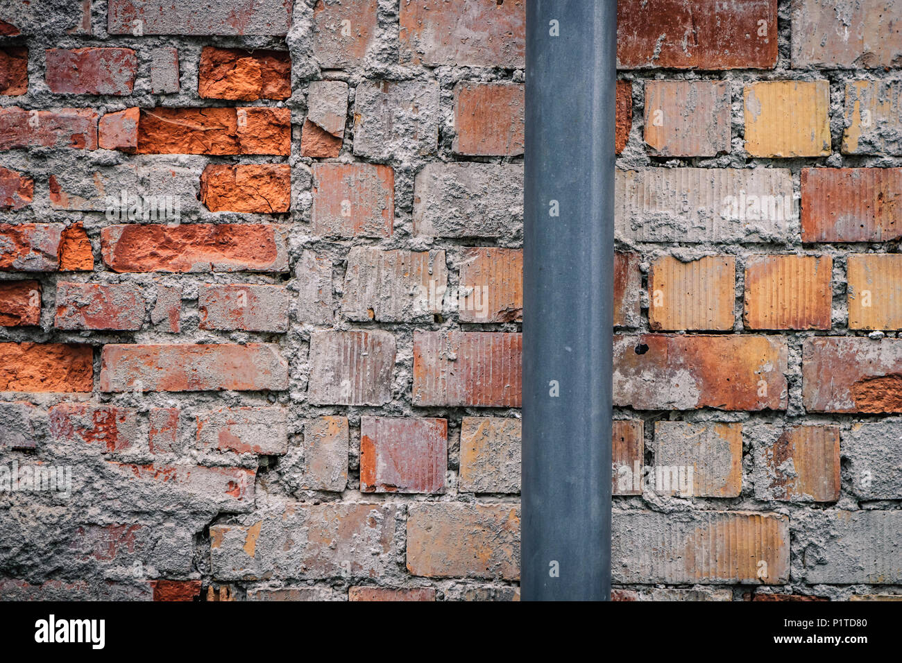 Grey plastic tube on a rugged brick wall. Background texture concept