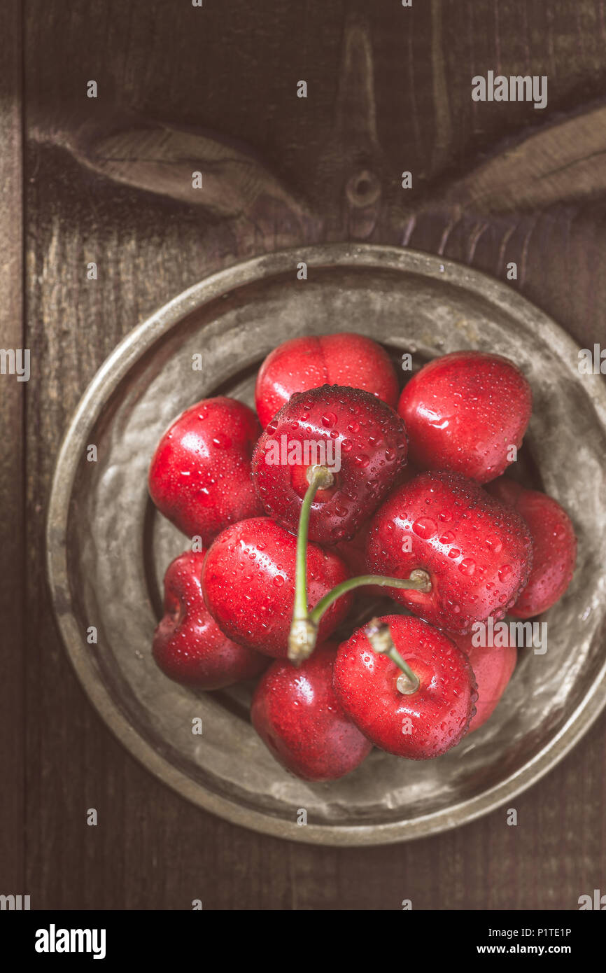Wet Fresh Red Cherries in Rustic Plate Stock Photo