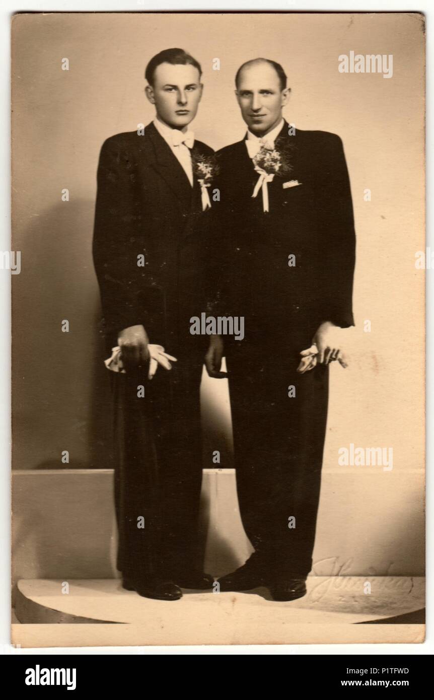 ZLIN, THE CZECHOSLOVAK REPUBLIC - CIRCA 1920s: Vintage photo shows two men (groom and his best man) pose in photography studio. Retro black & white photography. Stock Photo