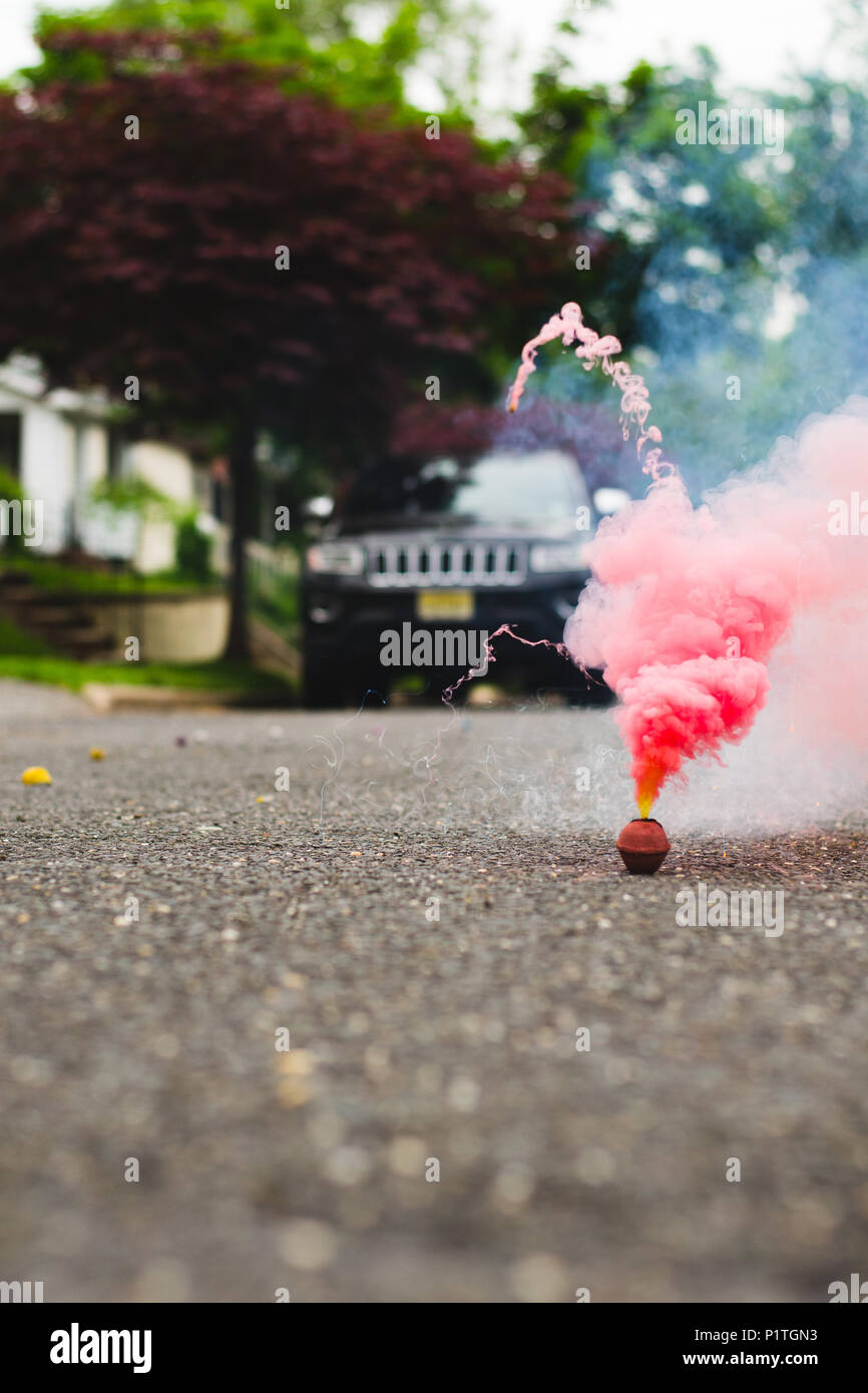 Red smoke bomb in the street smoking Stock Photo - Alamy