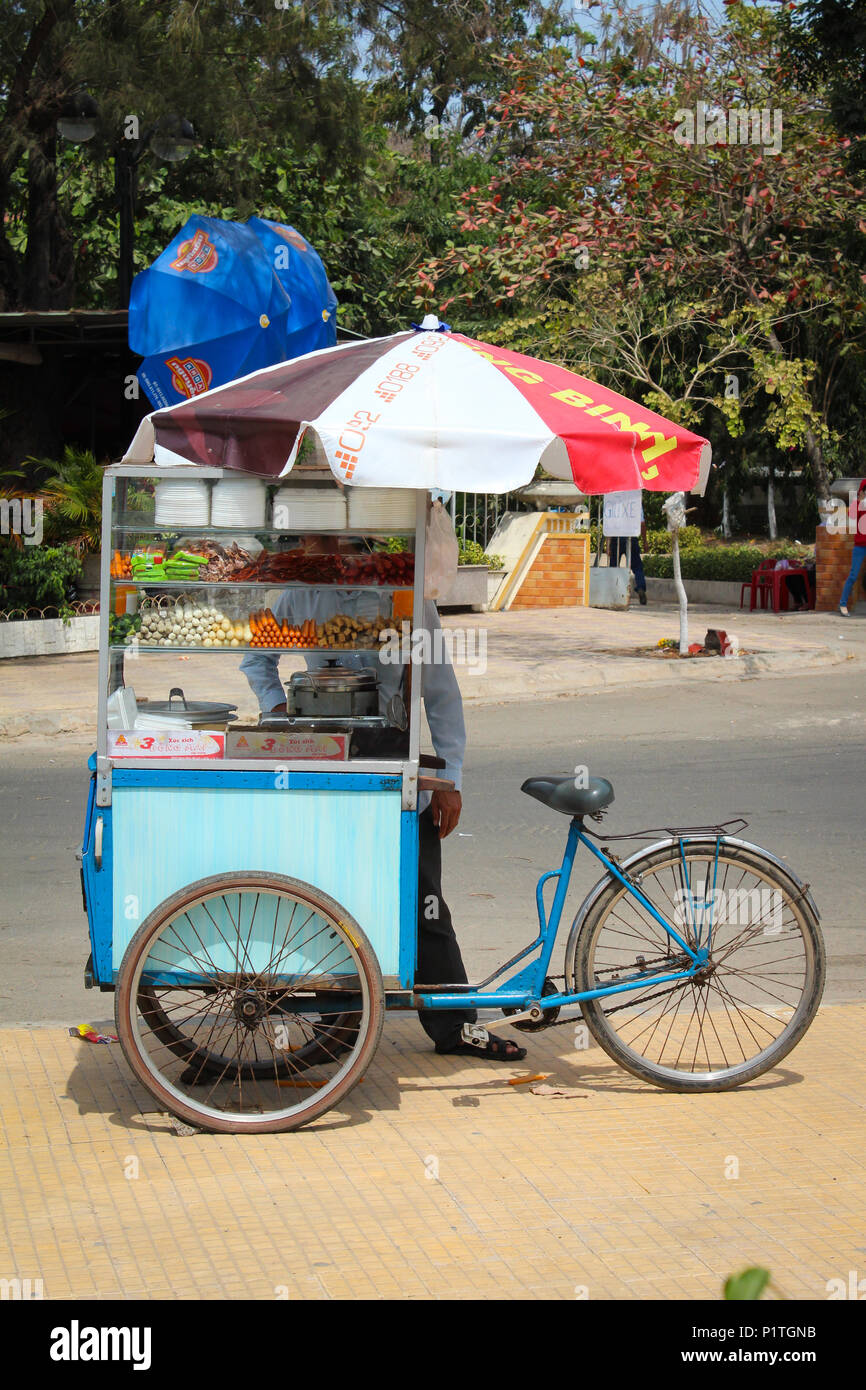 Phan Thiet  , Vietnam - January 2014: Man selling street food snacks from bicycle market stall   Phan Thiet  , Vietnam Stock Photo
