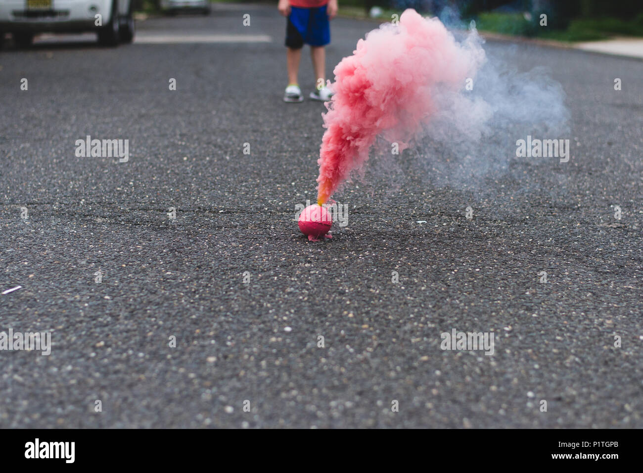 Red smoke bomb in the street smoking with a child watching in the background  Stock Photo - Alamy