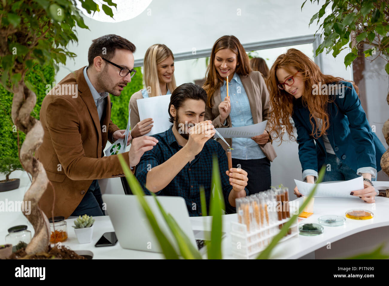 Team of university biologists  analysing the sample of plant in the test tube, watering it with drops of nutritious fluid. Stock Photo