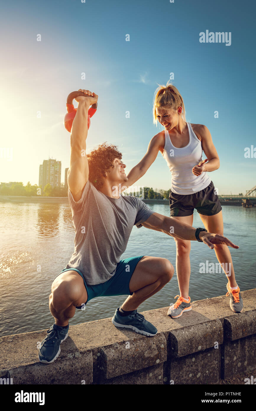 Young fitness couple doing workout with kettlebell on the wall by