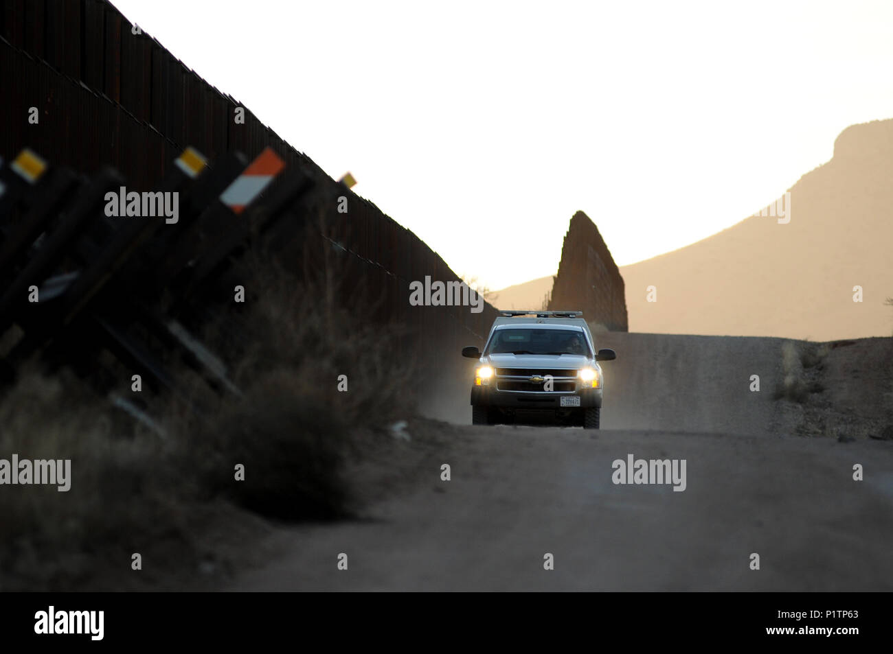 A U.S. Border Patrol agent drives on a dirt road along the U.S./Mexico ...