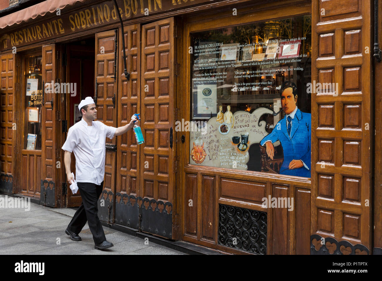 Madrid, Spain: A worker cleans the front window of Restaurante Sobrino de Botín. Originally founded in 1725 as Casa Botín, it is known as the oldest c Stock Photo