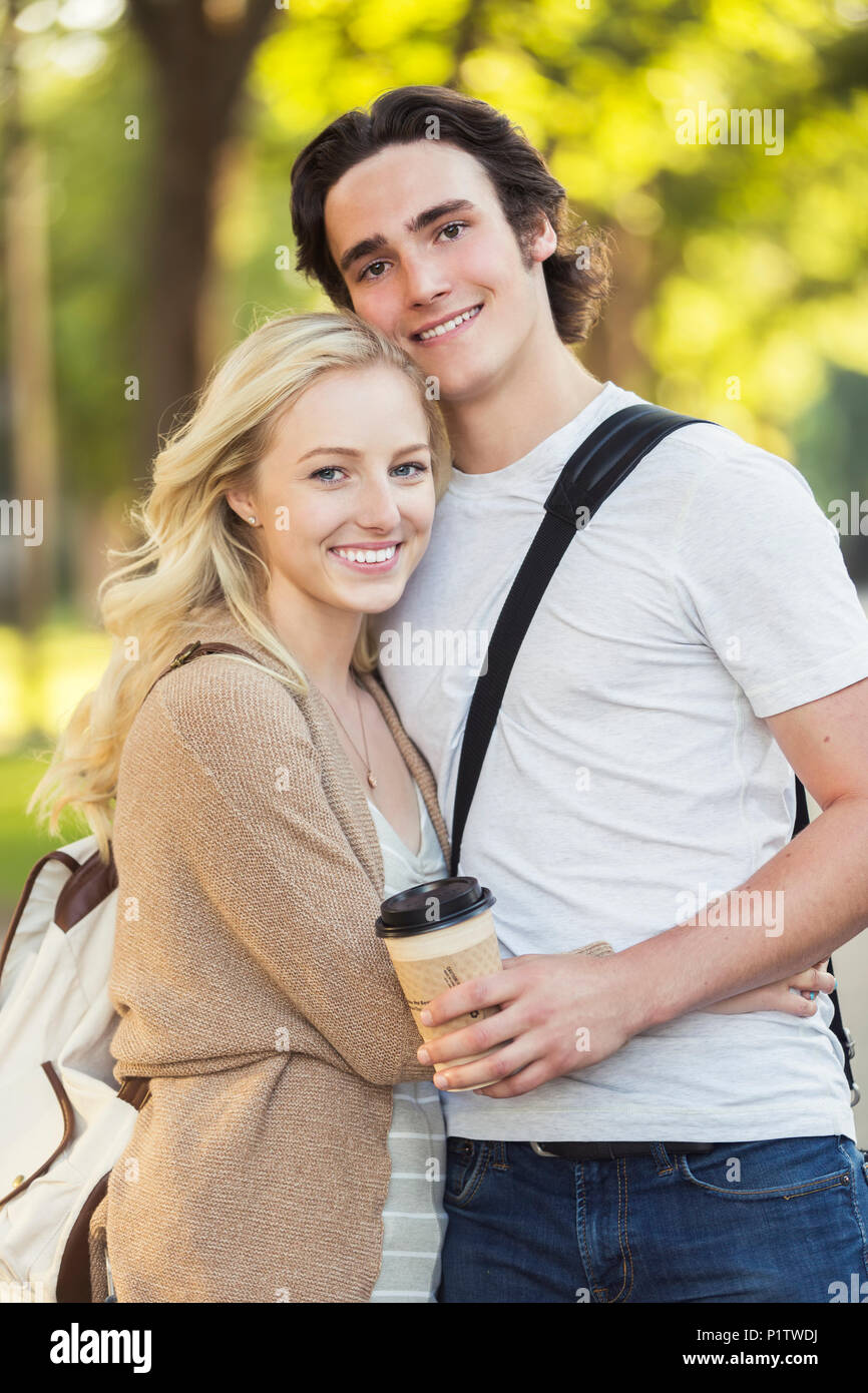 A young couple shares a romantic moment together in an embrace while outside on the university campus; Edmonton, Alberta, Canada Stock Photo